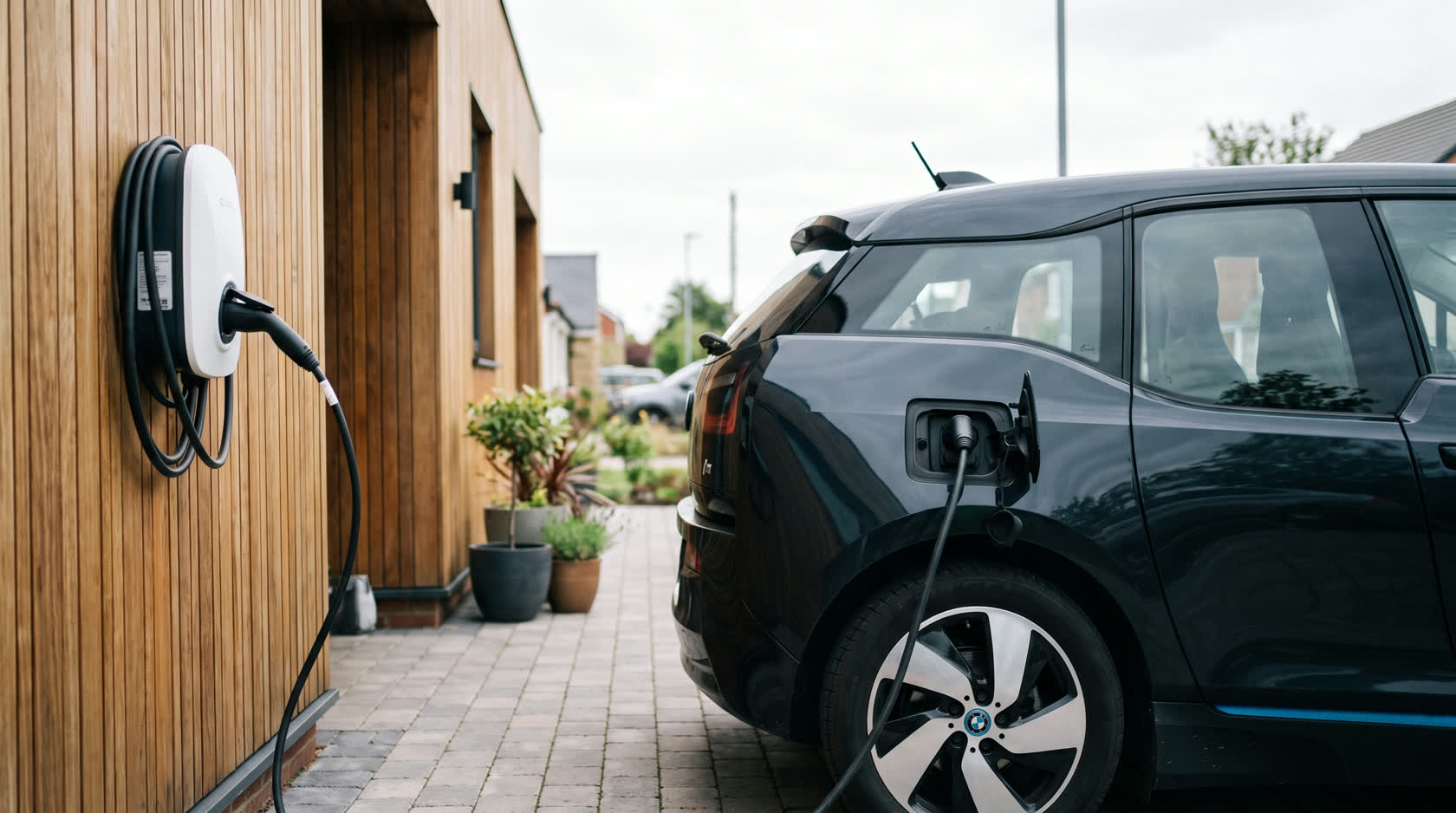 Wallbox an einer Hauswand lädt ein E-Auto in der Einfahrt